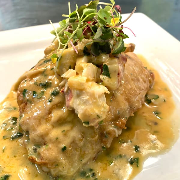 Golden-brown schnitzel covered in a creamy sauce with herbs and topped with microgreens.